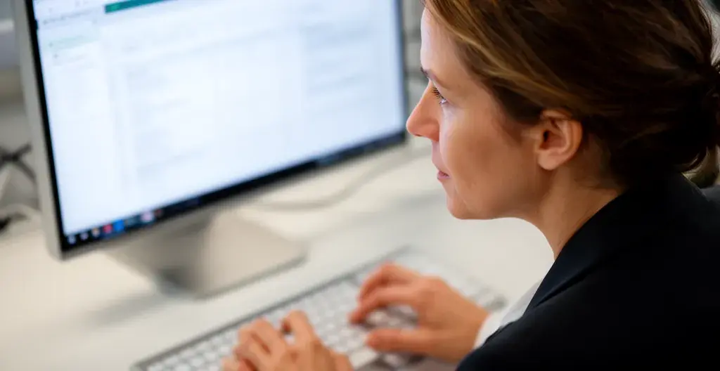 Responsable RH française analysant les effectifs sur écran d'ordinateur dans un bureau moderne